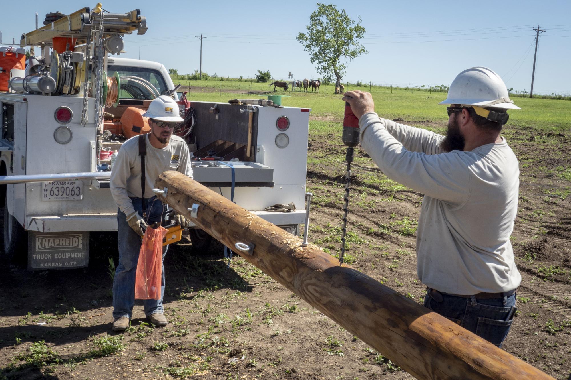 Bluestem linemen prepare a pole to be set in the ground.