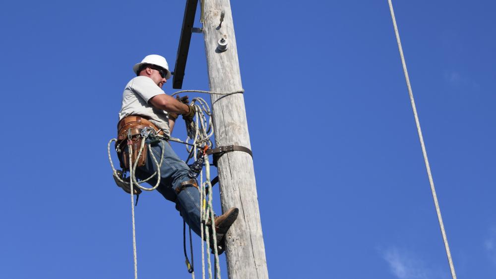 Lineman climbs and electric power pole